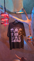 Black t-shirt with white graphic design on a surface with decorative elements